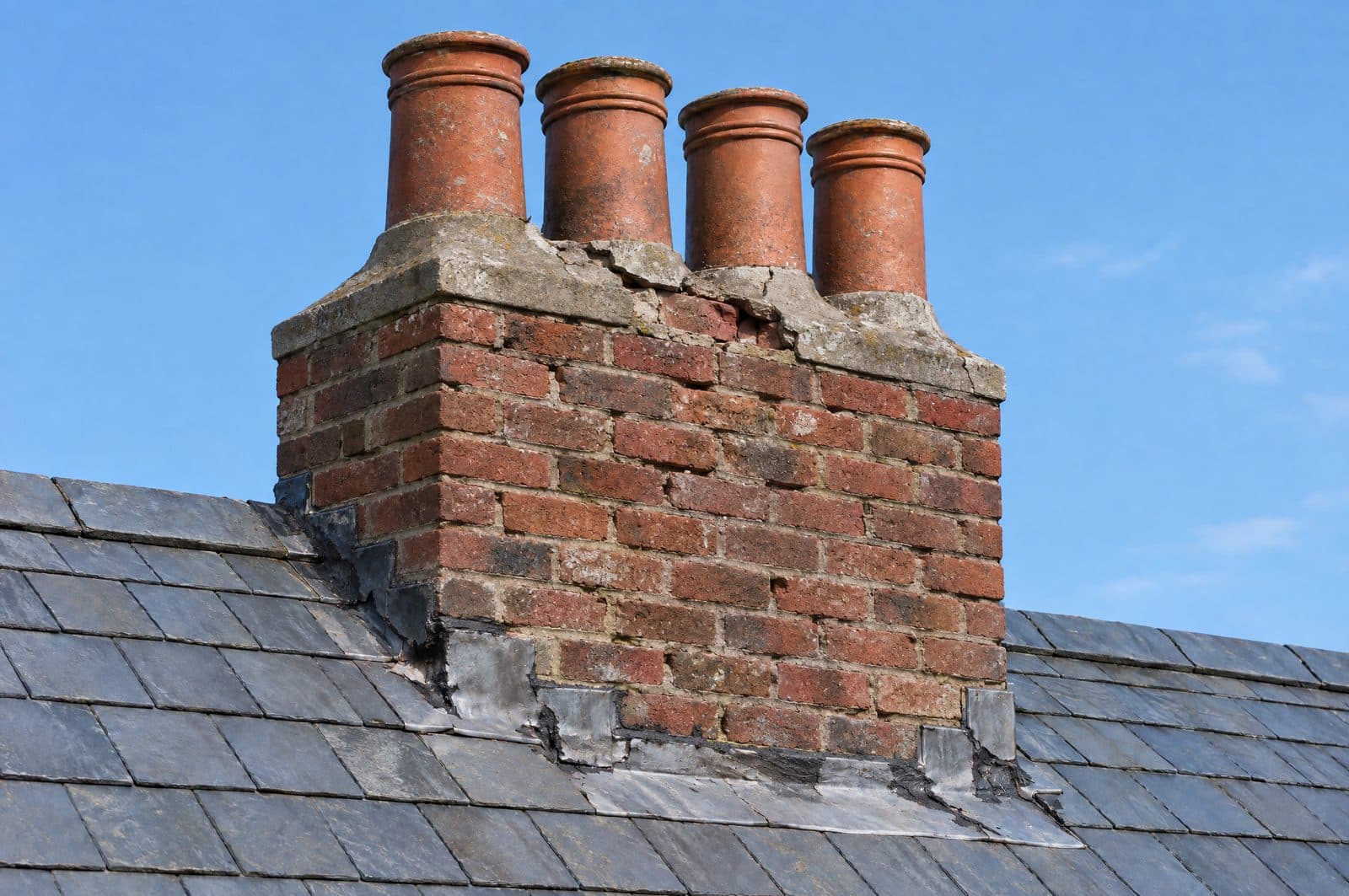 A brick chimney with eroded mortar joints, cracked flaunching and old lead smeared with mastic
