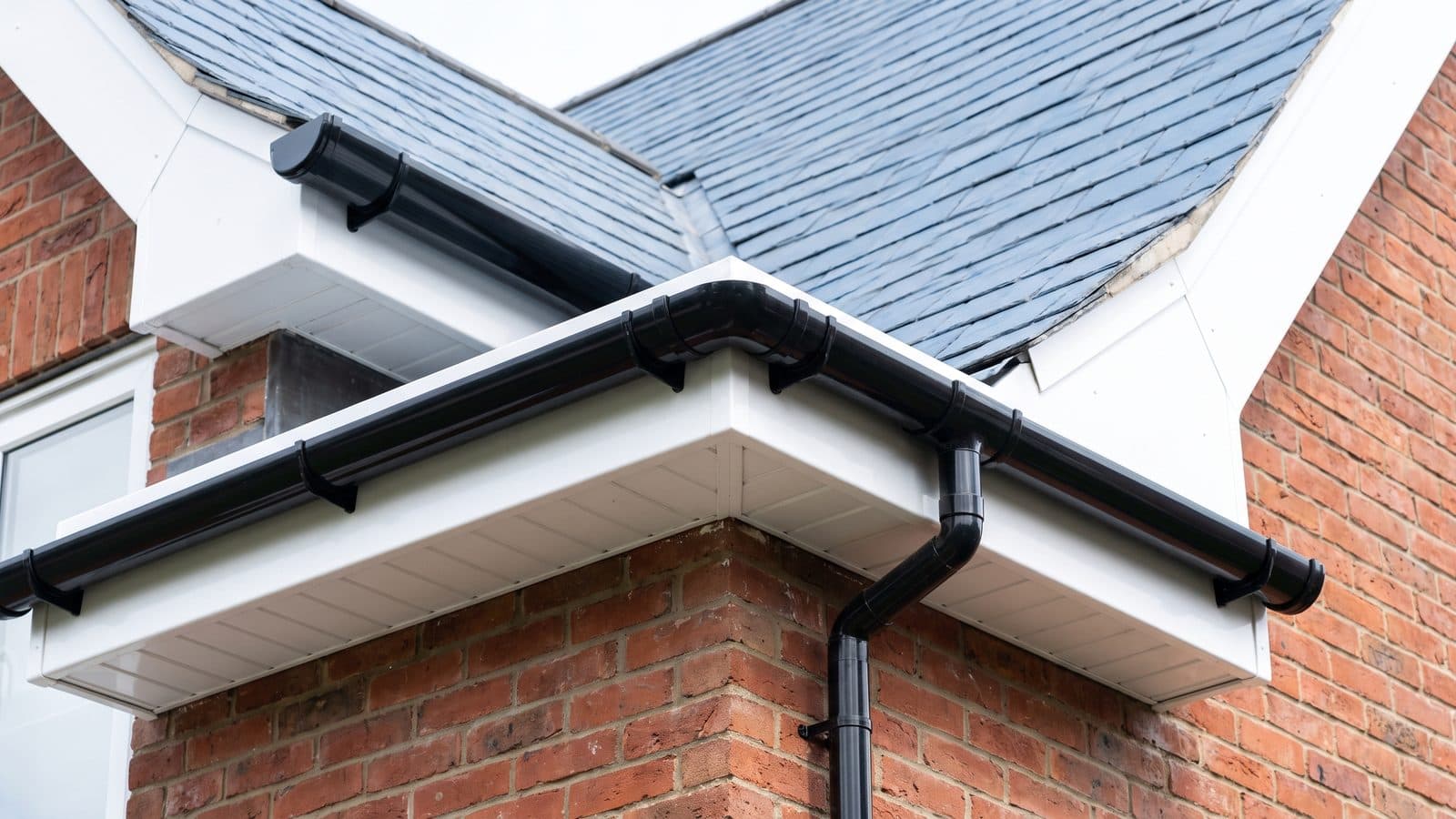 A new run of black half-round guttering with white fascia and soffit along the eaves