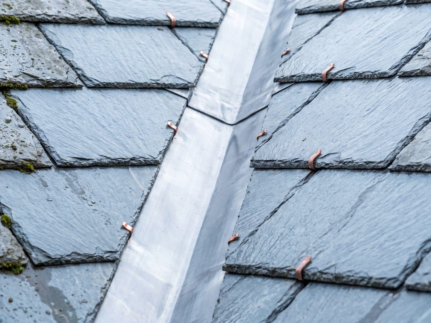 A newly formed lead valley running between two slate roof slopes, with slates cut cleanly along both sides