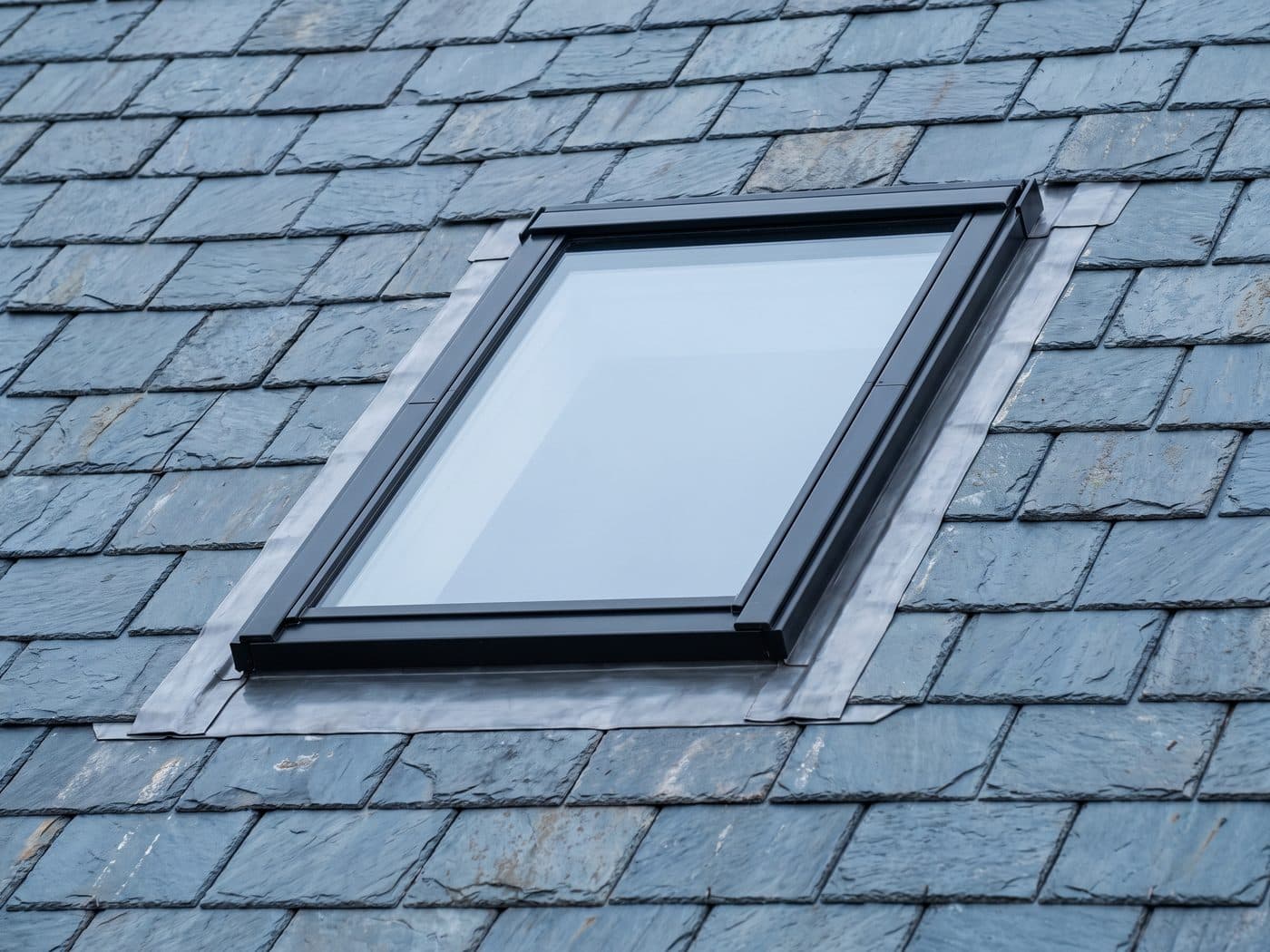 A flush conservation rooflight installed in a slate roof with lead flashing dressed neatly around all four sides