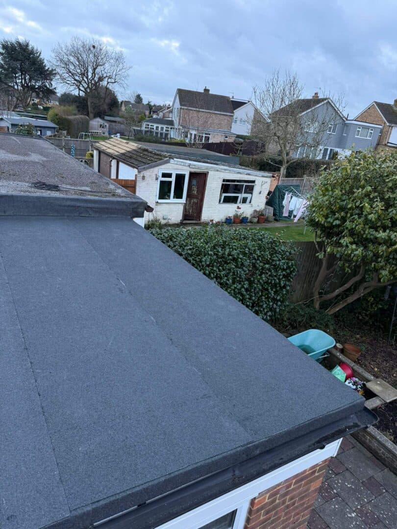 A new flat roof on a single-storey extension, finished with edge trims, gardens beyond