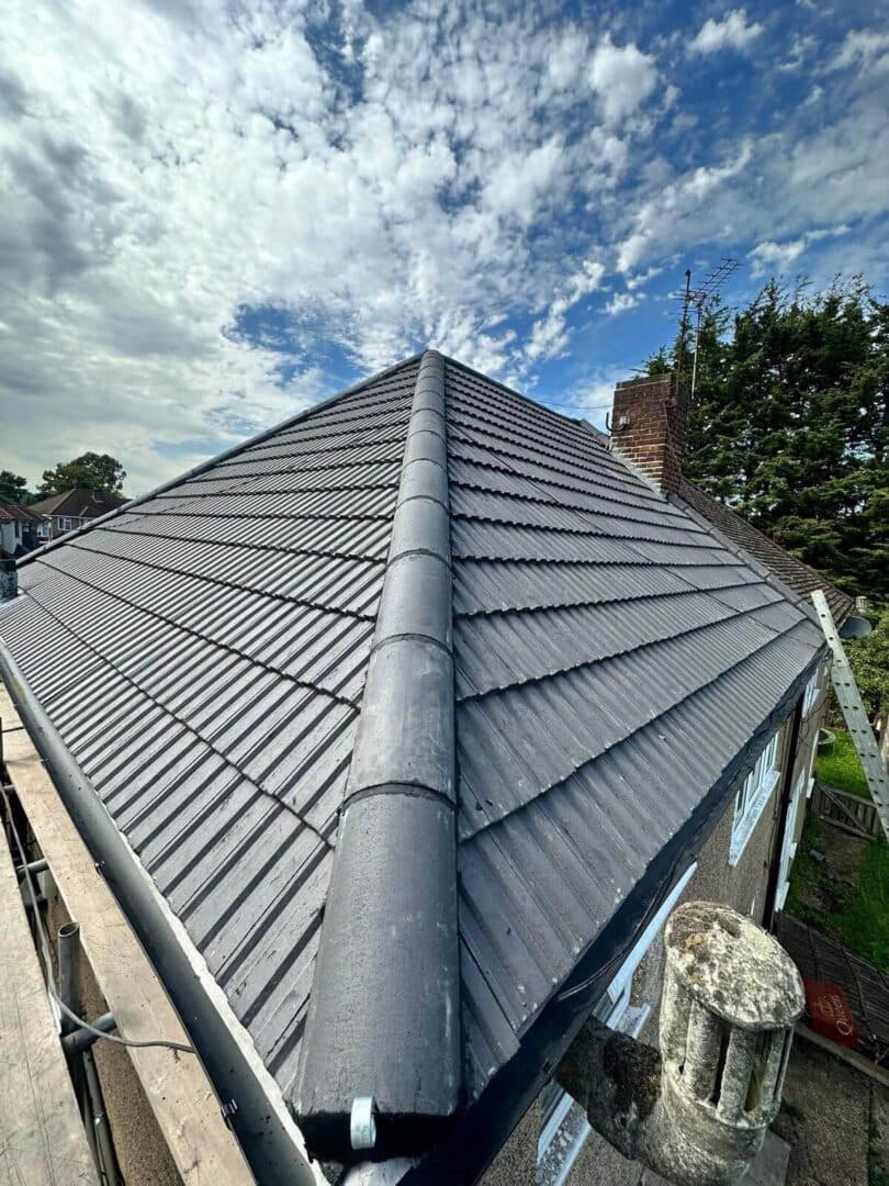 A grey interlocking tiled roof with a dry-fix ridge, photographed along the ridge from the scaffold